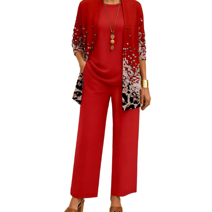 Model wearing the red set, the cardigan fading into a white and black speckled print with small studs, over a plain top and wide-leg trousers. 5