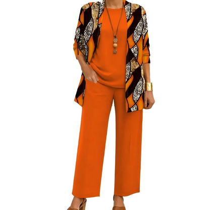 Model wearing the orange set, the cardigan in bold diagonal panels mixing leopard print, gold tones and brown, over a plain top and trousers. 9