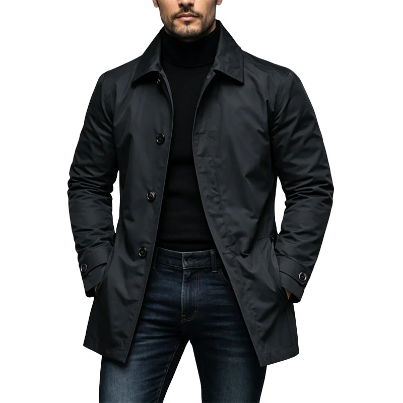 Model wearing the single-breasted trench coat in black over a black roll-neck and dark jeans, hands in pockets, front view. 1