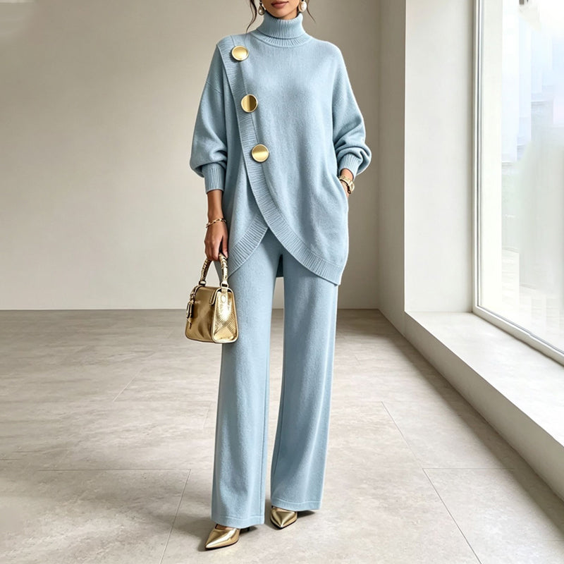 Model wears the knit set in pale blue, with a gold handbag and gold pointed shoes, in a bright room. 1