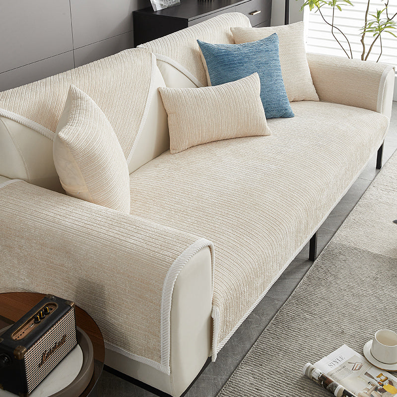 Cream chenille cover on a sofa with white piped edging, one blue cushion and a magazine and cup nearby. 3