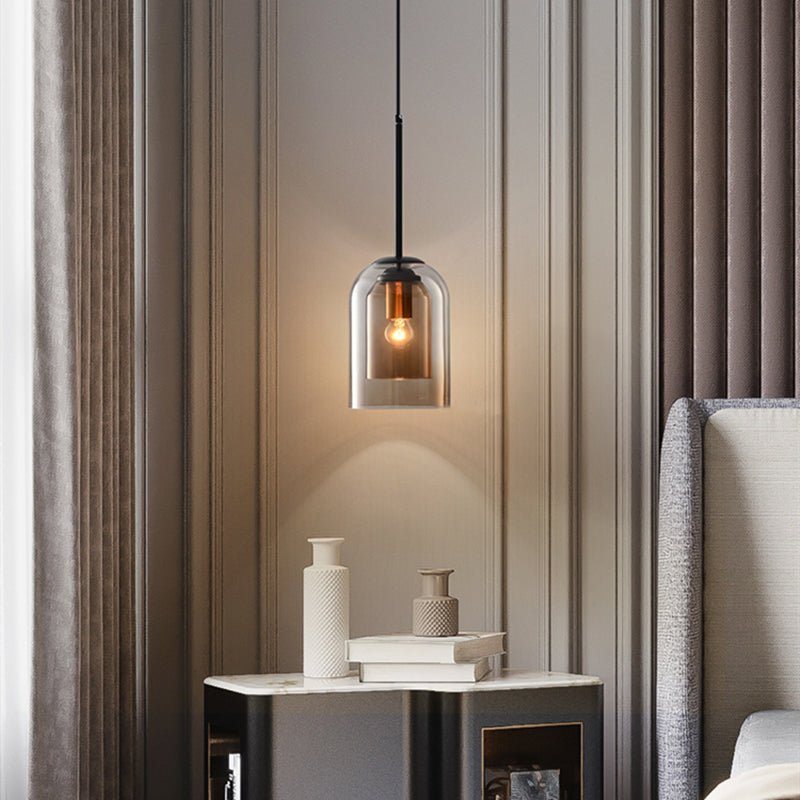 Single amber glass pendant light with a lit bulb hanging above a marble-topped bedside table 3