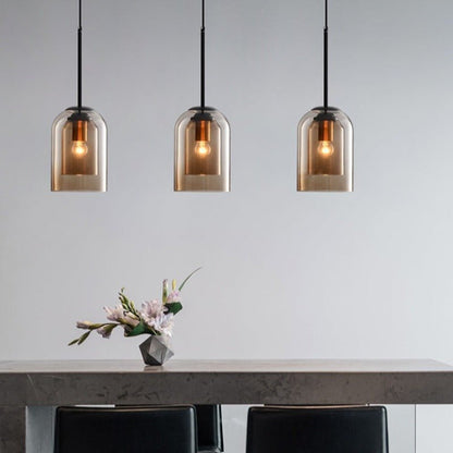Three amber glass pendant lights hanging in a line above a dining table with a flower vase 6