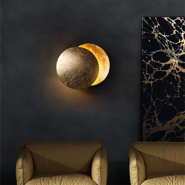 Lamp in gold finish on a dark wall above two olive armchairs, next to marbled artwork 5