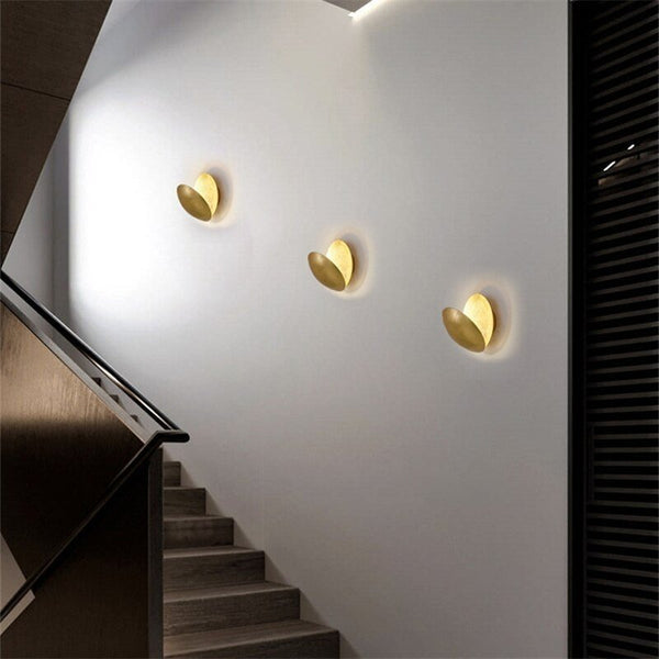 Three lamps in a row on a white stairwell wall, discs angled open in a leaf shape 7