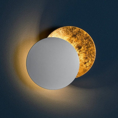 White front disc lamp on a navy wall, rear gold-leaf disc glowing warmly behind 8