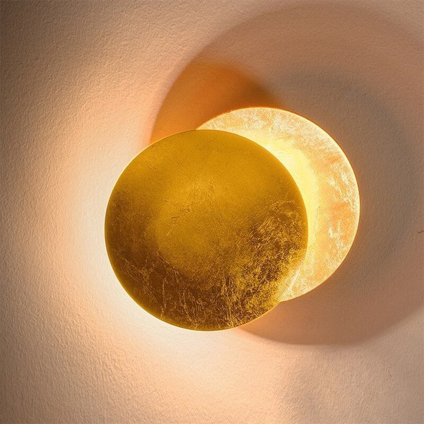 Gold wall lamp with the front disc offset to reveal the illuminated back disc, shown close up 12