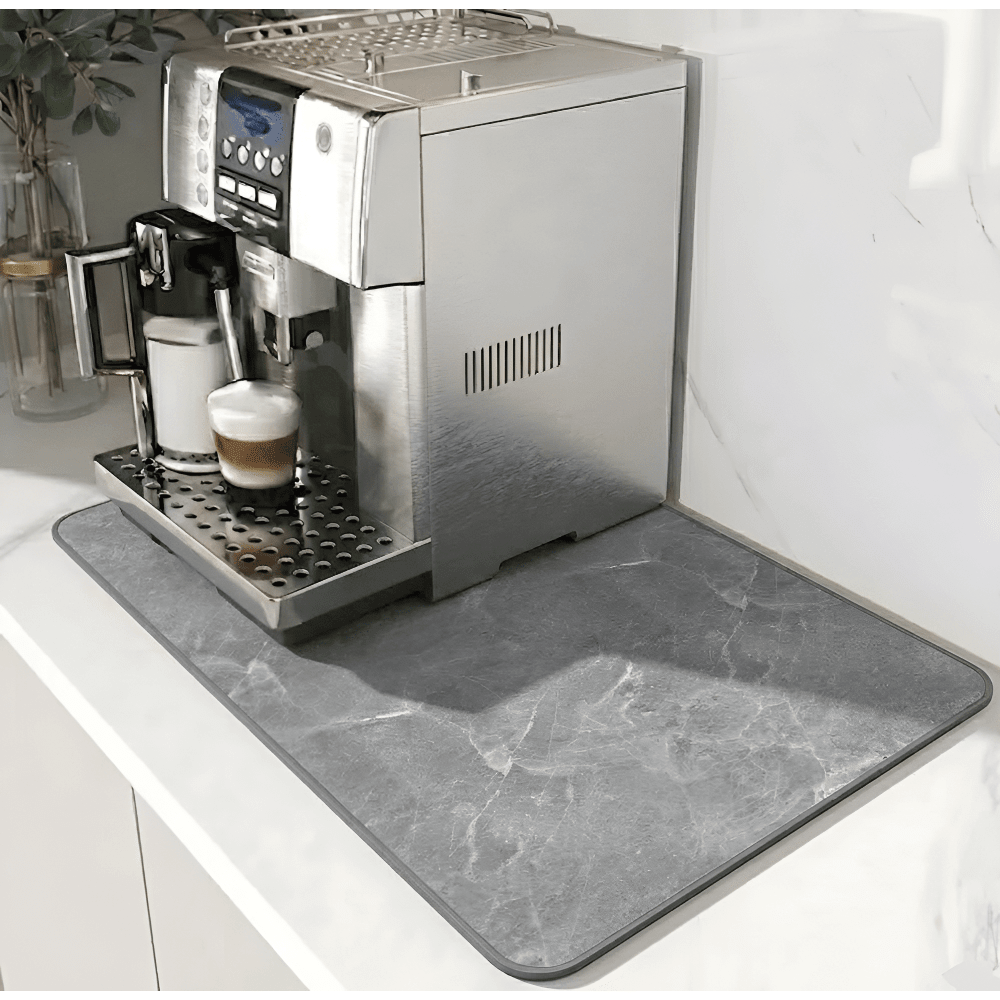 Grey marble-effect mat with a darker grey edge border, placed under a silver coffee machine on a white counter. 12