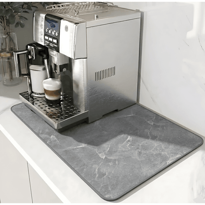 Grey marble-effect mat with a darker grey edge border, placed under a silver coffee machine on a white counter. 12