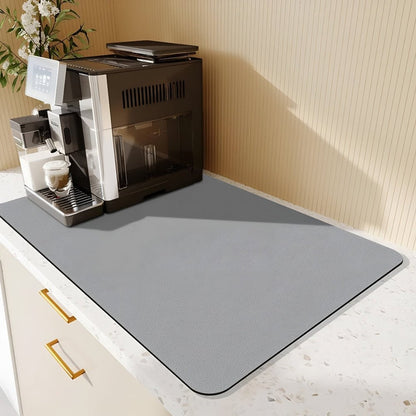 Plain light grey mat under a black and silver coffee machine on a speckled worktop, with cream cabinets below. 8