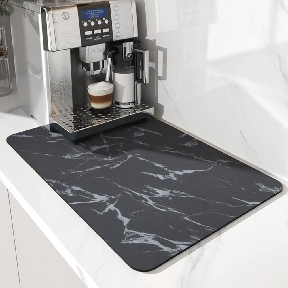 Black mat with white marble veining, set under a silver coffee machine on a white marble worktop. 4