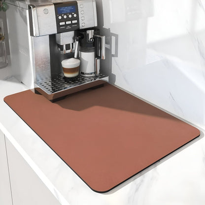 Plain terracotta brown mat in front of a silver coffee machine making a latte, on a white marble worktop. 10