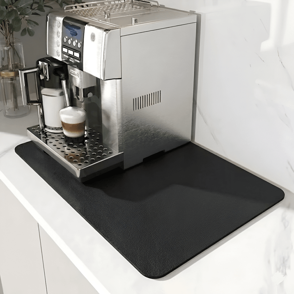 Plain black mat with a subtle leather-like grain under a silver coffee machine on a white marble counter. 9