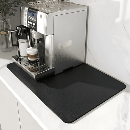 Plain black mat with a subtle leather-like grain under a silver coffee machine on a white marble counter. 9