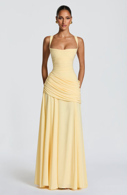 Full-length front view of the pale yellow maxi dress on a model standing straight, with arms by her sides and the skirt falling to the floor. 5