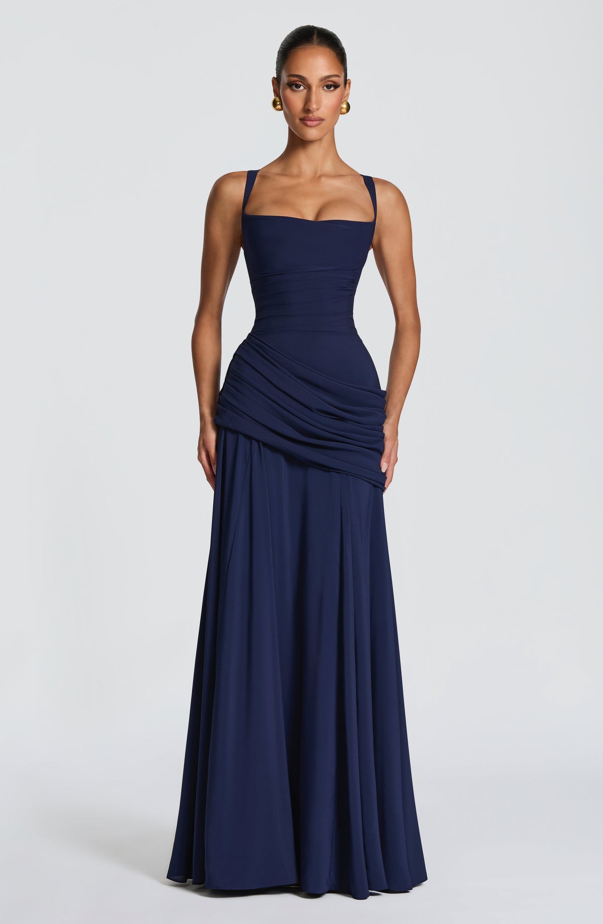 Navy version worn by a model facing forward, with gold earrings, square neckline, wide straps and draped hip detail. 5
