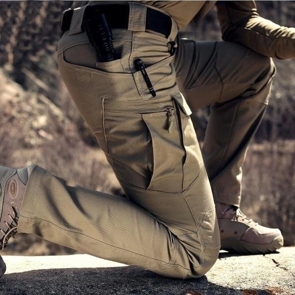 Close-up of a kneeling model in khaki trousers, showing the large zipped cargo pocket and a pen in the hip pocket 2