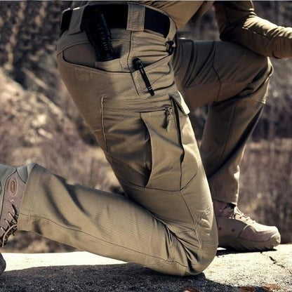 Close-up of a kneeling model in khaki trousers, showing the large zipped cargo pocket and a pen in the hip pocket 2