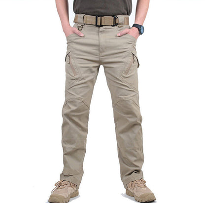 Front view of sand-coloured cargo trousers on a model with hands in pockets, showing zipped thigh pockets 1