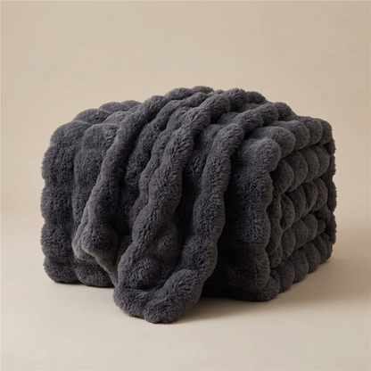 Dark grey bubble-textured blanket folded and draped over itself against a neutral backdrop 14