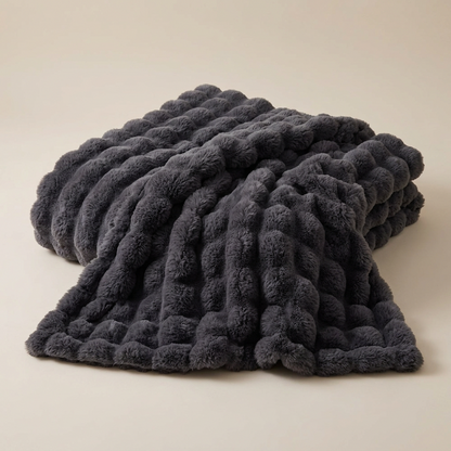 Dark grey plush blanket with a raised bubble texture laid out on a neutral background 14