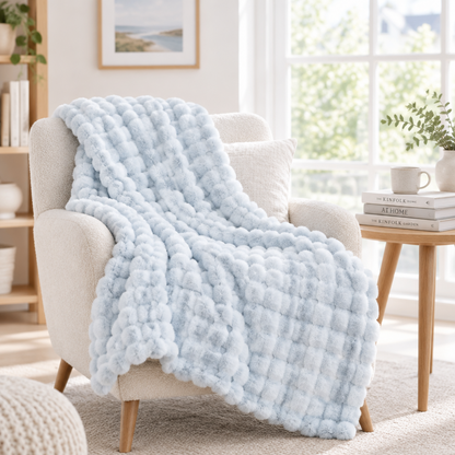Pale blue bubble-textured throw draped over a cream armchair near a bright window 17