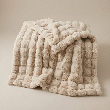 Beige bubble-textured plush blanket folded loosely on a plain neutral background 13