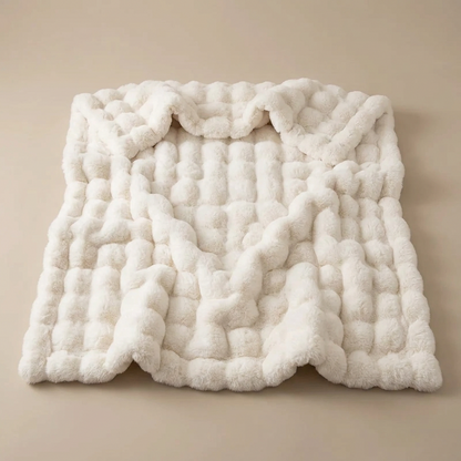 Cream-white bubble-textured plush blanket laid flat on a beige background with slightly ruffled edges 16