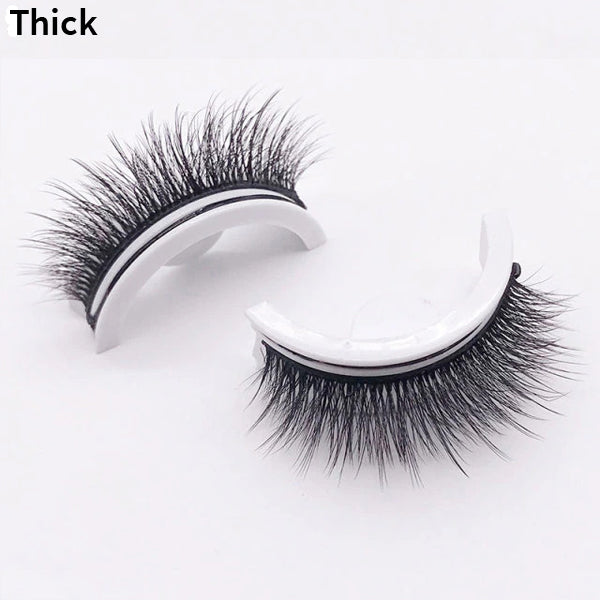 Pair of thick, dense lashes on curved white holders, one upright and one on its side, shown against a plain pale background. 12