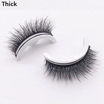 Pair of thick, dense lashes on curved white holders, one upright and one on its side, shown against a plain pale background. 12