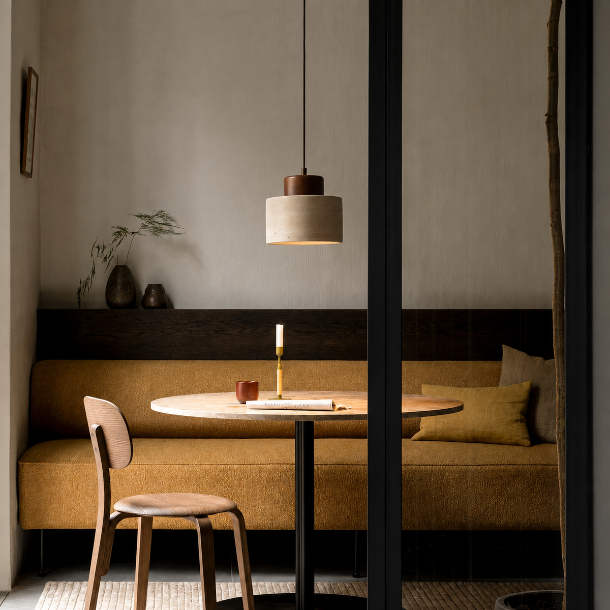 Single pendant hanging over a round table and mustard banquette seat in a moody, softly lit nook 4