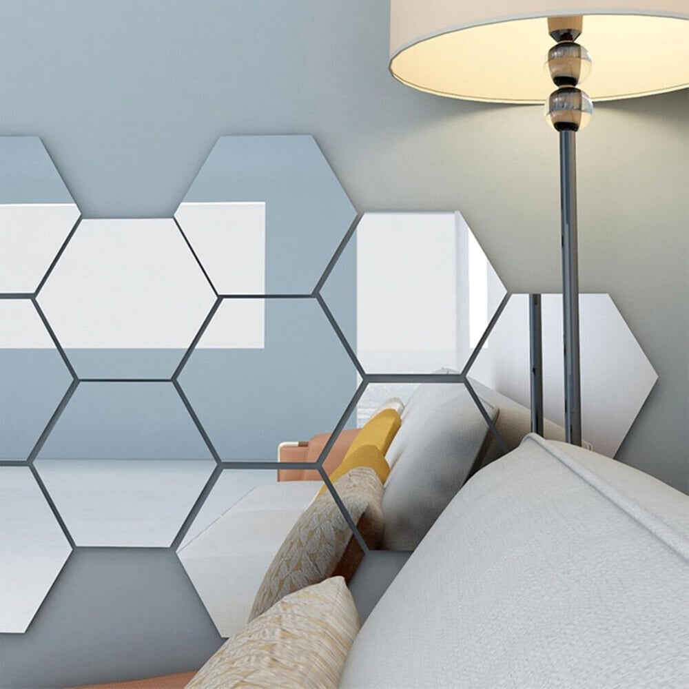 Hexagonal mirror tiles on a blue-grey wall beside a lamp, reflecting a sofa with yellow and beige cushions. 6