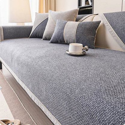 Dark charcoal grey woven sofa cover with braided edge, shown with grey cushions and a white cup on a saucer. 12