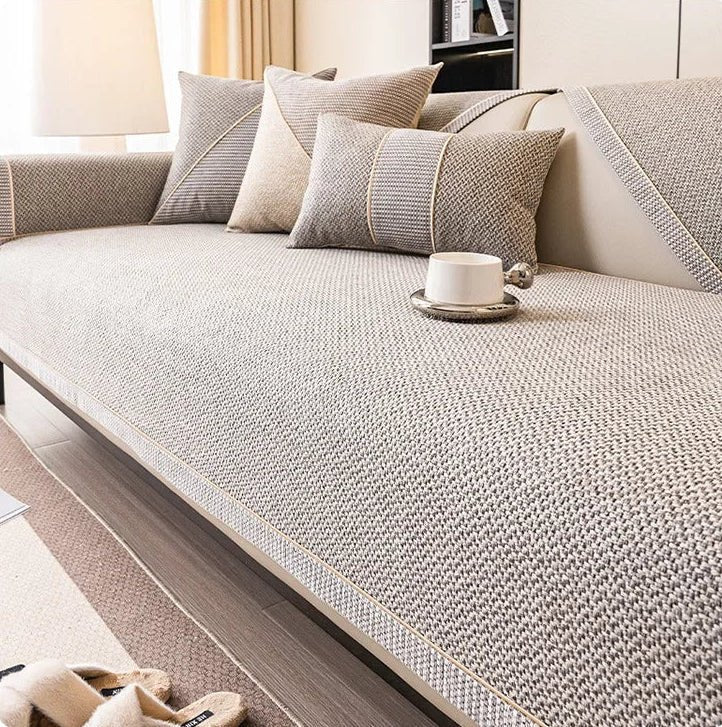 Greige woven sofa cover with pale braided edging, matching cushions and a white cup on a metal saucer. 7