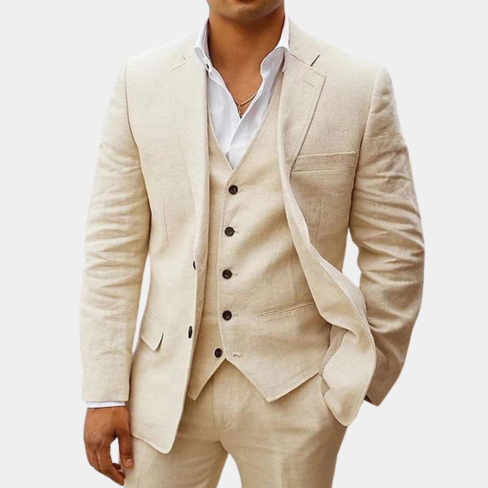 Model in a cream three-piece suit with five-button vest, white open-collar shirt and one hand in trouser pocket. 1