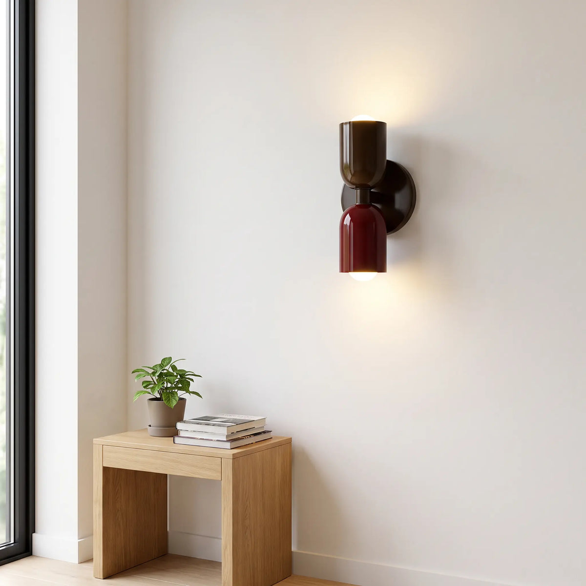 Dark brown and burgundy wall lamp with both bulbs lit on a white wall, above a small oak table with a plant and books. 10