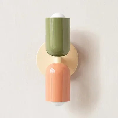 Single wall lamp with a green upper shade, cream backplate and peach lower shade, shown against a plain pale wall. 19