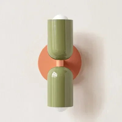 Two-tone wall lamp with olive green glossy shades on a terracotta round backplate, mounted on a pale wall. 21