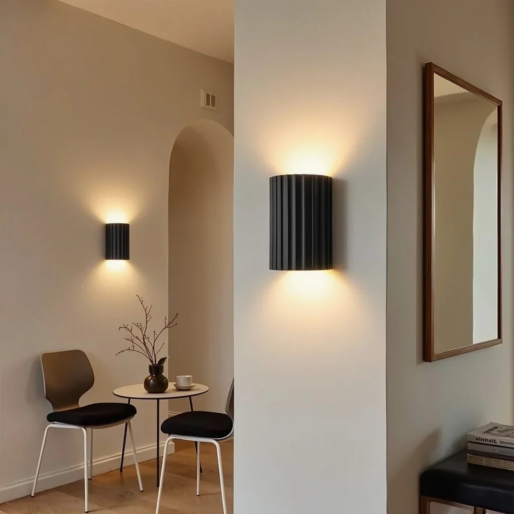 Two black fluted wall lights in a neutral room with a small round table, chairs and mirror 7