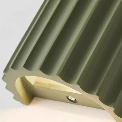 Close-up of a green fluted wall light's underside, showing the ridged edge and a small recessed LED 14