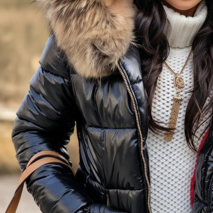 Close-up of the shiny black quilted body, gold-toned front zip and fur hood edge, worn over a white knit jumper. 3