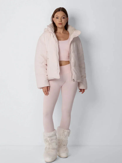 Full-length front view of the pale pink puffer jacket worn open over a matching pink crop top and leggings 10