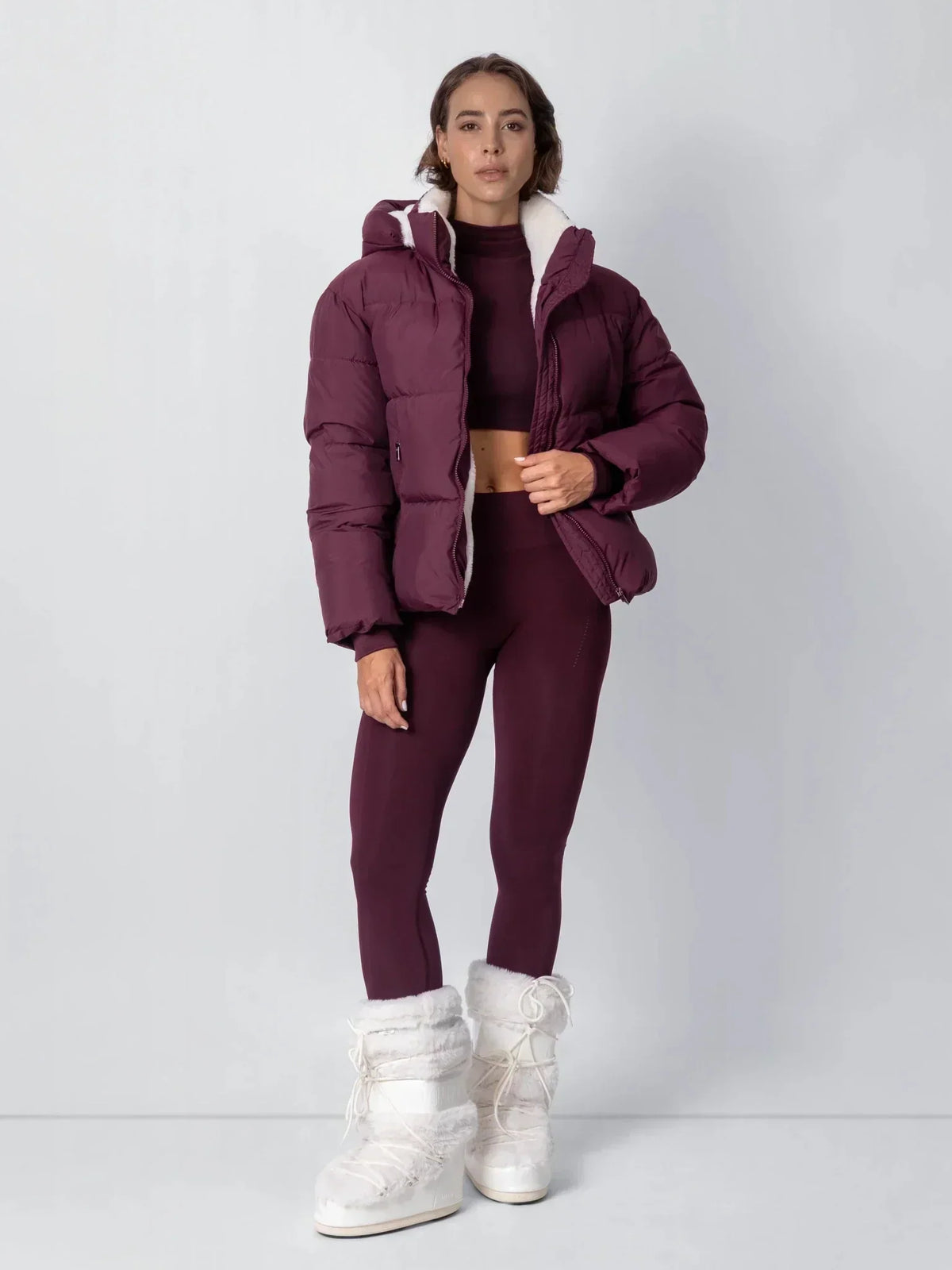 Full-length view of the burgundy puffer jacket worn open with matching leggings and cream fluffy boots 17