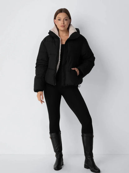 Full-length view of the black puffer jacket with cream fleece collar, worn with black leggings and tall black boots 13