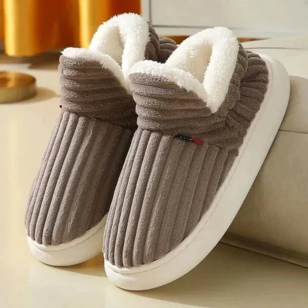 Pair of brown ribbed plush slippers with white fleece lining and chunky white soles, placed on a cream floor. 3