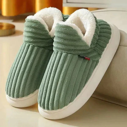 Pair of green ribbed plush slippers with fluffy white lining and thick white soles, leaning against a sofa. 4