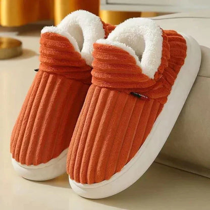 Pair of burnt orange ribbed plush slippers with fluffy white lining and chunky white soles, resting by a sofa. 6