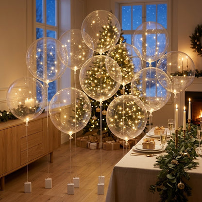 Cluster of lit clear balloons on tall strings near a Christmas tree and festive table 3