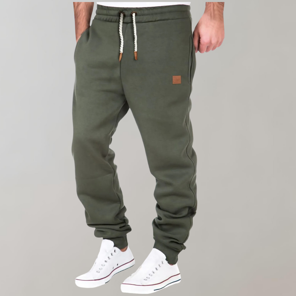 Olive green joggers worn with white trainers, braided drawstring and small leather-look patch on hip 3