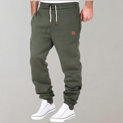 Olive green joggers worn with white trainers, braided drawstring and small leather-look patch on hip 3